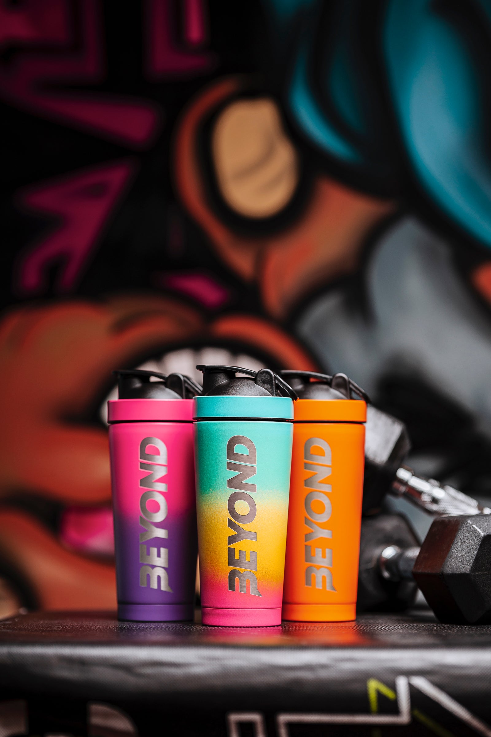 Three colourful Beyond Shakers bottles in a gym